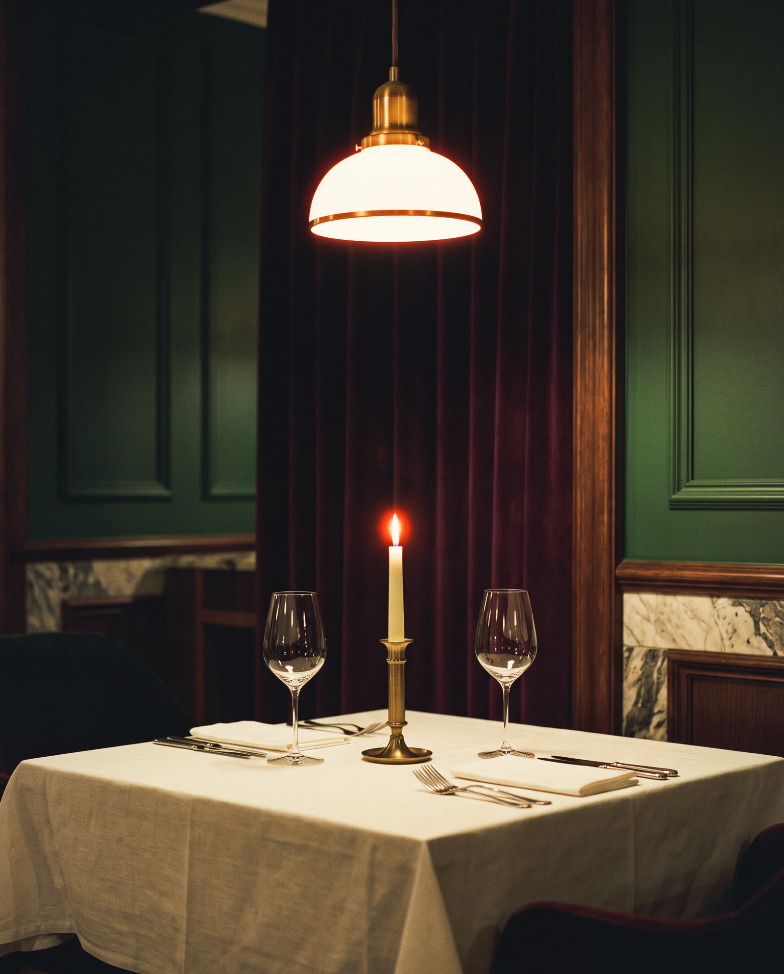 A set table under one lamp in the hotel restaurant at night